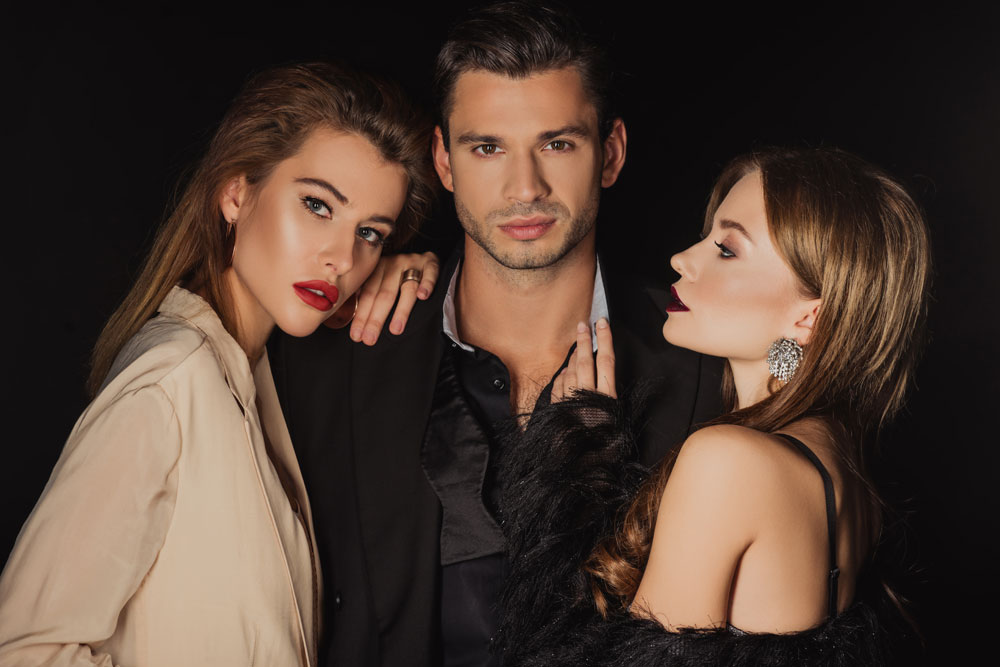 Zwei elegante Frauen posieren mit gutaussehendem Mann